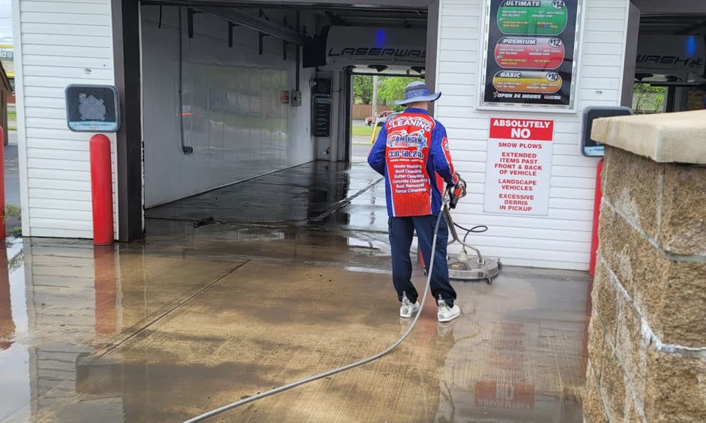 Power washer performing power washing on concrete