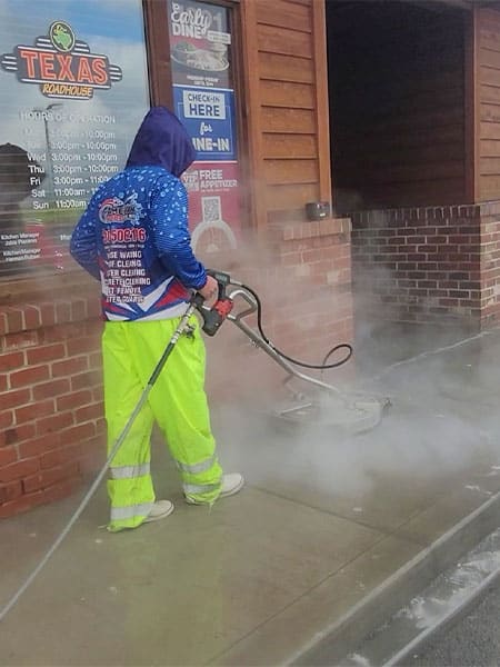 Pressure washer performing pressure washing on the sidewalk
